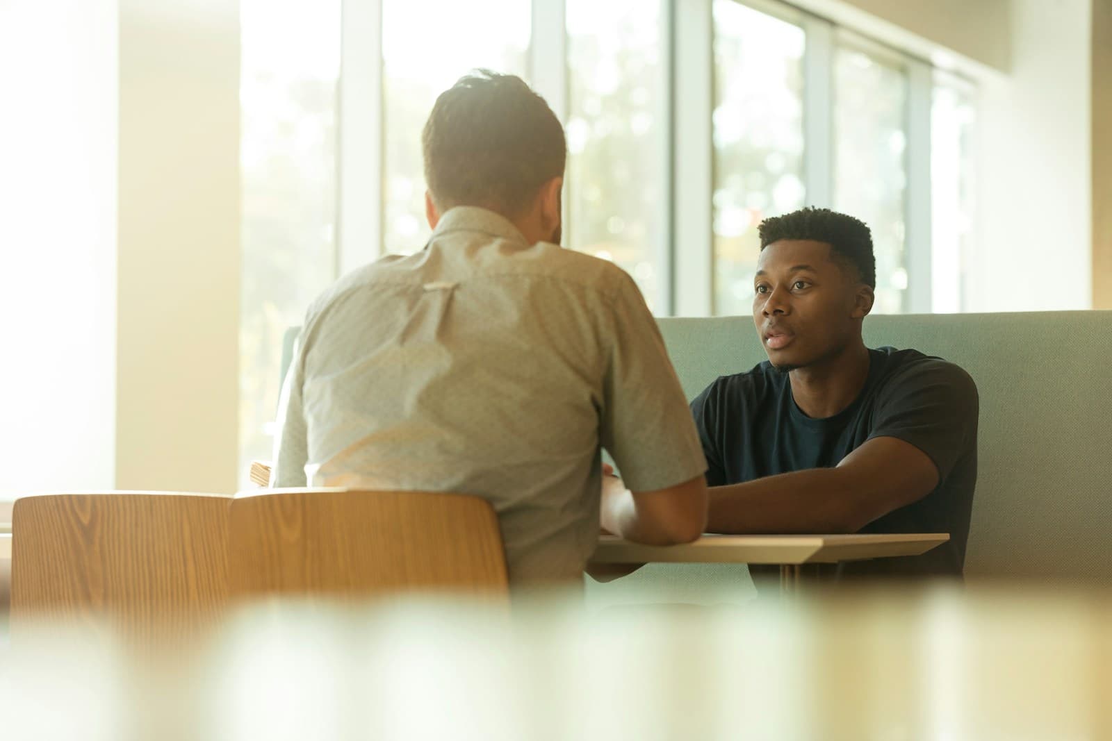 Two people sitting apart in a quiet room during a difficult conversation